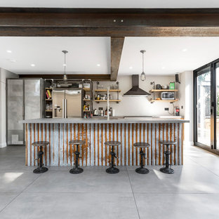 Idee per una grande cucina industriale con lavello integrato, ante lisce, ante in legno scuro, top in cemento, paraspruzzi in mattoni, elettrodomestici in acciaio inossidabile, pavimento in cemento, isola e pavimento grigio