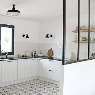 Inspiration for a mid-sized industrial u-shaped open plan kitchen with an integrated sink, louvered cabinets, white cabinets, quartz benchtops, white splashback, stainless steel appliances, cement tiles, no island, grey floor, ceramic splashback and black benchtop.