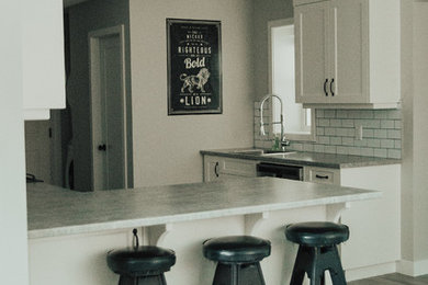 Mid-sized transitional l-shaped vinyl floor eat-in kitchen photo in Vancouver with a single-bowl sink, shaker cabinets, white cabinets, laminate countertops, white backsplash, subway tile backsplash, stainless steel appliances and a peninsula