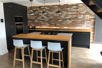This is an example of a medium sized industrial open plan kitchen in Other with flat-panel cabinets, grey cabinets, wood worktops and an island.