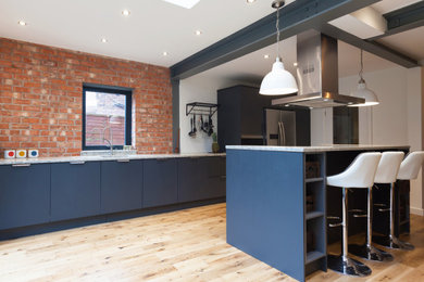 Photo of a large urban single-wall open plan kitchen in Cheshire with a submerged sink, flat-panel cabinets, grey cabinets, quartz worktops, multi-coloured splashback, brick splashback, stainless steel appliances, light hardwood flooring, an island and grey worktops.