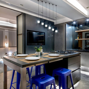 Modelo de cocina comedor urbana, pequeña, con armarios con paneles lisos, salpicadero metalizado, salpicadero con efecto espejo, suelo de cemento, una isla, puertas de armario en acero inoxidable y suelo gris