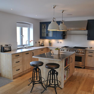 Mid-sized industrial u-shaped kitchen in Kent with beige cabinets, zinc benchtops, stainless steel appliances, light hardwood floors and a peninsula.