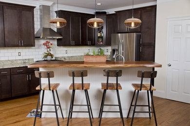 Example of a mid-sized urban l-shaped medium tone wood floor open concept kitchen design in New York with a double-bowl sink, wood countertops, white backsplash, subway tile backsplash, stainless steel appliances, an island, shaker cabinets and dark wood cabinets
