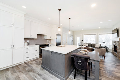 Example of a small transitional single-wall vinyl floor and brown floor open concept kitchen design in Other with an undermount sink, shaker cabinets, white cabinets, quartzite countertops, gray backsplash, subway tile backsplash, stainless steel appliances and an island