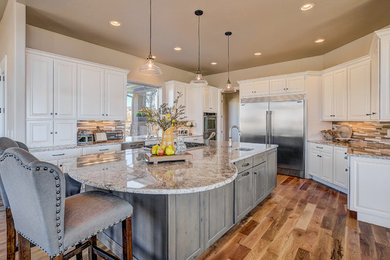 Large transitional u-shaped medium tone wood floor enclosed kitchen photo in Denver with an undermount sink, raised-panel cabinets, white cabinets, granite countertops, beige backsplash, matchstick tile backsplash, stainless steel appliances and an island