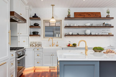 Example of a trendy l-shaped medium tone wood floor, brown floor and shiplap ceiling kitchen design in Calgary with a farmhouse sink, recessed-panel cabinets, white cabinets, quartz countertops, white backsplash, brick backsplash, paneled appliances, an island and white countertops