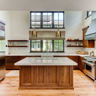 Modelo de cocina en U, clásica, con fregadero sobremueble, armarios estilo shaker, puertas de armario de madera oscura, electrodomésticos de acero inoxidable, suelo de madera en tonos medios, una isla y suelo marrón