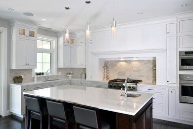 Example of a large transitional l-shaped dark wood floor and brown floor open concept kitchen design in Ottawa with shaker cabinets, white cabinets, an island, an undermount sink, quartz countertops, beige backsplash, stone tile backsplash and stainless steel appliances