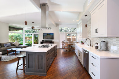 Open concept kitchen - transitional galley medium tone wood floor open concept kitchen idea in Orange County with a farmhouse sink, shaker cabinets, white cabinets, beige backsplash, stainless steel appliances and an island