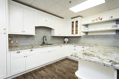 Foto på ett vintage u-kök, med en dubbel diskho, skåp i shakerstil, vita skåp, granitbänkskiva, grått stänkskydd, stänkskydd i stenkakel, mörkt trägolv och en halv köksö