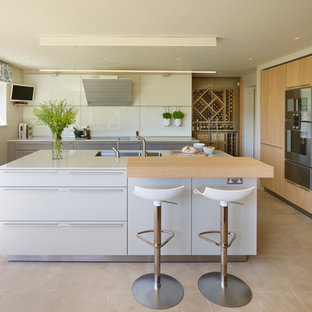 This is an example of a medium sized contemporary l-shaped kitchen/diner in Other with a double-bowl sink, flat-panel cabinets, white cabinets, composite countertops, white splashback, glass sheet splashback, stainless steel appliances, an island, beige floors and white worktops.