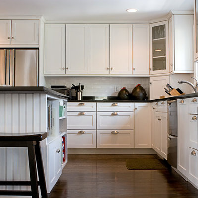 Inspiration for a mid-sized craftsman l-shaped medium tone wood floor and brown floor open concept kitchen remodel in San Francisco with shaker cabinets, white cabinets, granite countertops, white backsplash, subway tile backsplash, stainless steel appliances, an island and black countertops