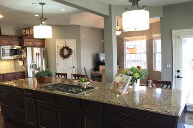 Transitional l-shaped dark wood floor kitchen photo in St Louis with an undermount sink, recessed-panel cabinets, dark wood cabinets, quartzite countertops, beige backsplash, stone tile backsplash, stainless steel appliances and an island