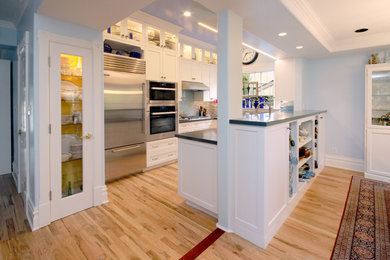 Photo of a medium sized traditional u-shaped kitchen/diner in San Francisco with shaker cabinets, white cabinets, engineered stone countertops, stainless steel appliances, a breakfast bar, multi-coloured splashback, matchstick tiled splashback, a submerged sink and light hardwood flooring.
