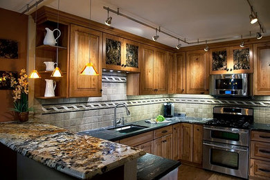 Inredning av ett amerikanskt mellanstort brun brunt kök, med en undermonterad diskho, luckor med upphöjd panel, skåp i mellenmörkt trä, granitbänkskiva, beige stänkskydd, stänkskydd i stenkakel, rostfria vitvaror, mellanmörkt trägolv, en halv köksö och brunt golv
