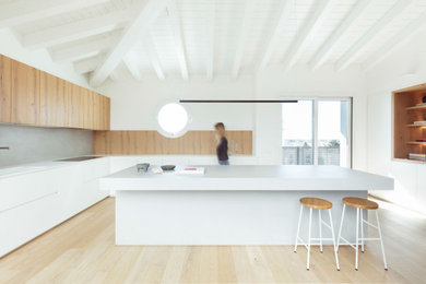 Foto di una grande cucina minimal chiusa con ante lisce, ante bianche, top in legno, paraspruzzi grigio, elettrodomestici neri, parquet scuro, pavimento marrone e top bianco