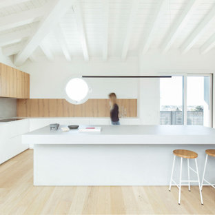Foto di una grande cucina minimal chiusa con ante lisce, ante bianche, top in legno, paraspruzzi grigio, elettrodomestici neri, parquet scuro, pavimento marrone e top bianco
