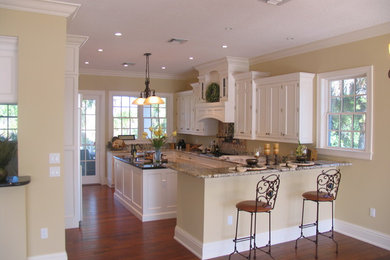 タンパにある広いトラディショナルスタイルのおしゃれなキッチン (落し込みパネル扉のキャビネット、白いキャビネット、パネルと同色の調理設備、グレーのキッチンカウンター) の写真