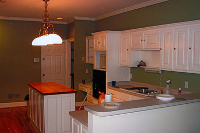 Wohnküche in L-Form mit weißen Schränken, schwarzen Elektrogeräten, dunklem Holzboden und Kücheninsel in Atlanta
