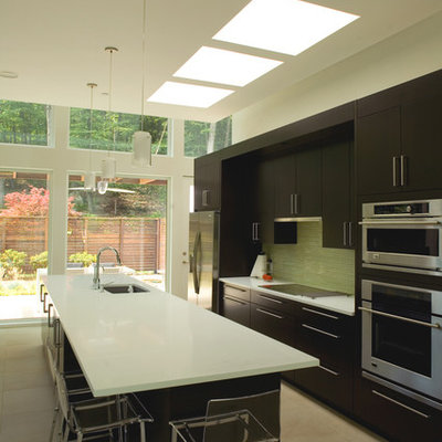Example of a minimalist galley kitchen design in New York with stainless steel appliances, flat-panel cabinets, dark wood cabinets and an undermount sink