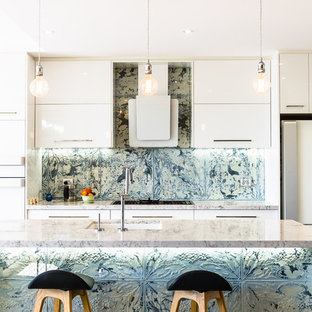 Contemporary galley kitchen in Sydney with an undermount sink, flat-panel cabinets, white cabinets, metallic splashback, white appliances, with island, brown floor and grey benchtop.
