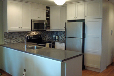 Open concept kitchen - small transitional u-shaped light wood floor open concept kitchen idea in New York with a single-bowl sink, recessed-panel cabinets, white cabinets, solid surface countertops, multicolored backsplash, mosaic tile backsplash, stainless steel appliances and a peninsula