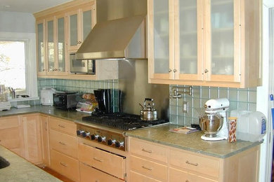 Example of a mid-sized classic medium tone wood floor and brown floor enclosed kitchen design in New York with glass-front cabinets, light wood cabinets, granite countertops, glass tile backsplash, stainless steel appliances and an island