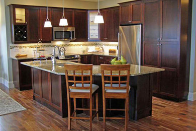 サクラメントにあるトラディショナルスタイルのおしゃれなアイランドキッチン (アンダーカウンターシンク、濃色木目調キャビネット、御影石カウンター、白いキッチンパネル、シルバーの調理設備、無垢フローリング) の写真