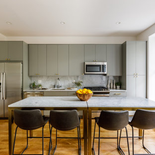 Contemporary kitchen appliance - Inspiration for a contemporary medium tone wood floor kitchen remodel in New York with an undermount sink, flat-panel cabinets, gray cabinets, white backsplash, stone slab backsplash, stainless steel appliances and white countertops