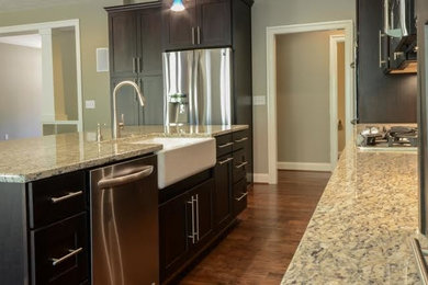 Mid-sized transitional galley medium tone wood floor open concept kitchen photo in Richmond with recessed-panel cabinets, dark wood cabinets, granite countertops, an island, multicolored backsplash, a farmhouse sink, matchstick tile backsplash and stainless steel appliances