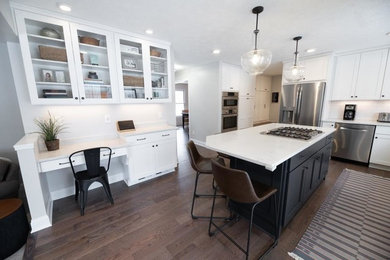 Mid-sized transitional l-shaped medium tone wood floor and gray floor eat-in kitchen photo in Cleveland with an undermount sink, recessed-panel cabinets, white cabinets, quartz countertops, white backsplash, porcelain backsplash, stainless steel appliances, an island and white countertops