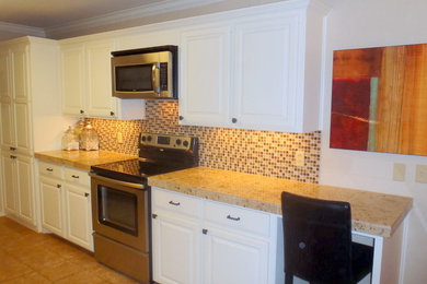 オースティンにあるトラディショナルスタイルのおしゃれなアイランドキッチン (レイズドパネル扉のキャビネット、白いキャビネット、御影石カウンター、石タイルのキッチンパネル、シルバーの調理設備) の写真