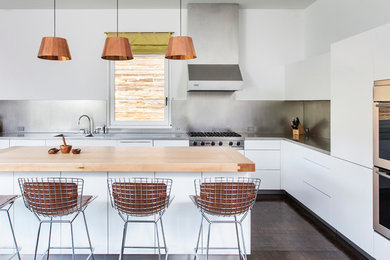 Inspiration för moderna kök, med en dubbel diskho, släta luckor, vita skåp, bänkskiva i rostfritt stål, stänkskydd med metallisk yta, rostfria vitvaror och en köksö