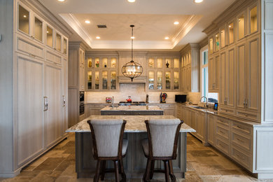 Inspiration for a large transitional u-shaped travertine floor and beige floor kitchen remodel in Other with an undermount sink, raised-panel cabinets, brown cabinets, quartzite countertops, subway tile backsplash, paneled appliances, two islands and white backsplash