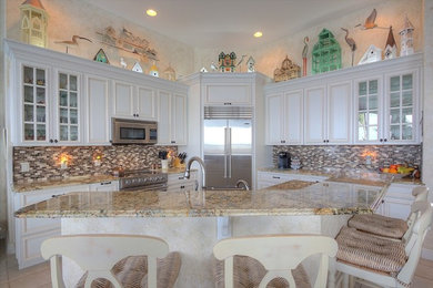 Mid-sized beach style l-shaped beige floor and ceramic tile kitchen photo in Miami with an island, white cabinets, granite countertops, multicolored backsplash, raised-panel cabinets, multicolored countertops, an undermount sink and stainless steel appliances