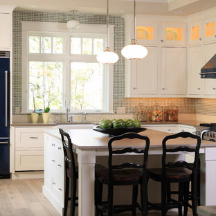 Open concept kitchen - mid-sized traditional l-shaped light wood floor open concept kitchen idea in Grand Rapids with a farmhouse sink, recessed-panel cabinets, white cabinets, green backsplash, glass tile backsplash, colored appliances and an island