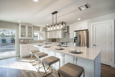 Mid-sized trendy l-shaped vinyl floor and brown floor open concept kitchen photo in Phoenix with an undermount sink, shaker cabinets, white cabinets, quartz countertops, multicolored backsplash, ceramic backsplash, stainless steel appliances, an island and white countertops