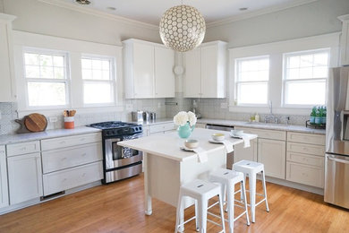Amerikansk inredning av ett kök, med vita skåp, rostfria vitvaror, ljust trägolv och en köksö