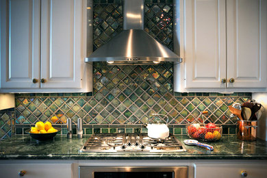 Bild på ett kök, med grönt stänkskydd, stänkskydd i keramik och rostfria vitvaror