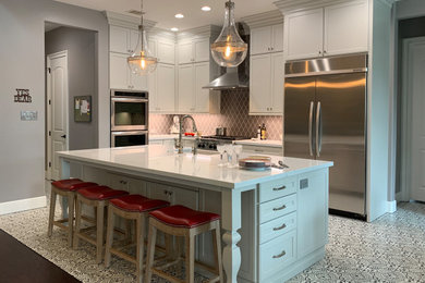 Example of a transitional l-shaped porcelain tile and multicolored floor kitchen design in Houston with a farmhouse sink, recessed-panel cabinets, white cabinets, quartz countertops, gray backsplash, ceramic backsplash, stainless steel appliances, an island and white countertops