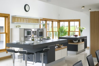 Bild på ett stort funkis kök, med en undermonterad diskho, släta luckor, grå skåp, bänkskiva i koppar, rostfria vitvaror, klinkergolv i porslin och flera köksöar