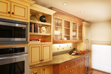 Inspiration for a mid-sized timeless galley light wood floor enclosed kitchen remodel in Orange County with a double-bowl sink, beaded inset cabinets, medium tone wood cabinets, granite countertops, green backsplash, ceramic backsplash, stainless steel appliances and no island
