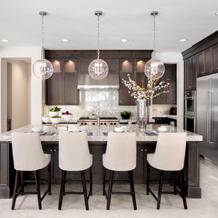 Transitional kitchen designs - Transitional l-shaped beige floor and marble floor kitchen photo in Orange County with dark wood cabinets, stainless steel appliances, an island, shaker cabinets, beige backsplash, stone slab backsplash and beige countertops