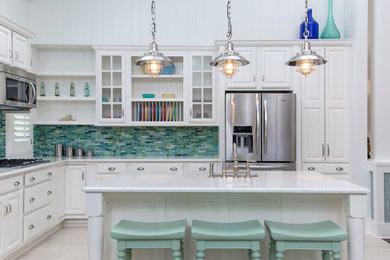 Beach style l-shaped kitchen photo in Miami with an undermount sink, raised-panel cabinets, white cabinets, green backsplash, mosaic tile backsplash, stainless steel appliances and an island