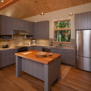 This is an example of a mid-sized country u-shaped eat-in kitchen in Seattle with an undermount sink, louvered cabinets, grey cabinets, granite benchtops, beige splashback, matchstick tile splashback, stainless steel appliances, medium hardwood floors and with island.