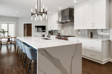Inspiration for a large modern l-shaped medium tone wood floor and brown floor enclosed kitchen remodel in Chicago with an undermount sink, flat-panel cabinets, white cabinets, quartz countertops, gray backsplash, porcelain backsplash, paneled appliances, an island and white countertops