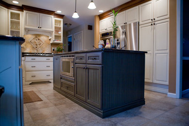 Eat-in kitchen - mid-sized traditional l-shaped porcelain tile eat-in kitchen idea in Chicago with an undermount sink, raised-panel cabinets, white cabinets, granite countertops, mosaic tile backsplash, stainless steel appliances and an island
