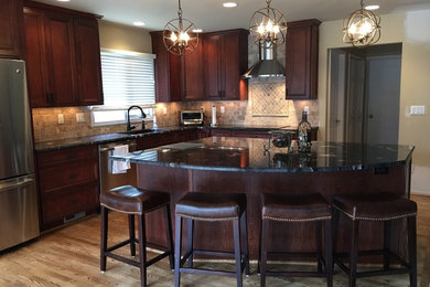 Example of a large classic l-shaped light wood floor eat-in kitchen design in Detroit with a double-bowl sink, recessed-panel cabinets, dark wood cabinets, granite countertops, beige backsplash, stone tile backsplash, stainless steel appliances and an island