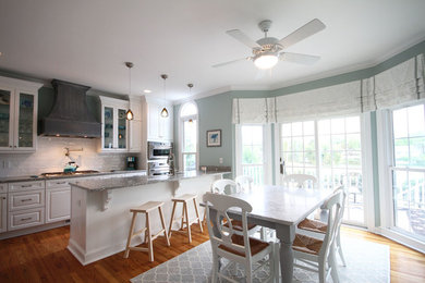 Example of a mid-sized beach style galley medium tone wood floor eat-in kitchen design in Charleston with a farmhouse sink, raised-panel cabinets, white cabinets, granite countertops, white backsplash, porcelain backsplash, stainless steel appliances and a peninsula